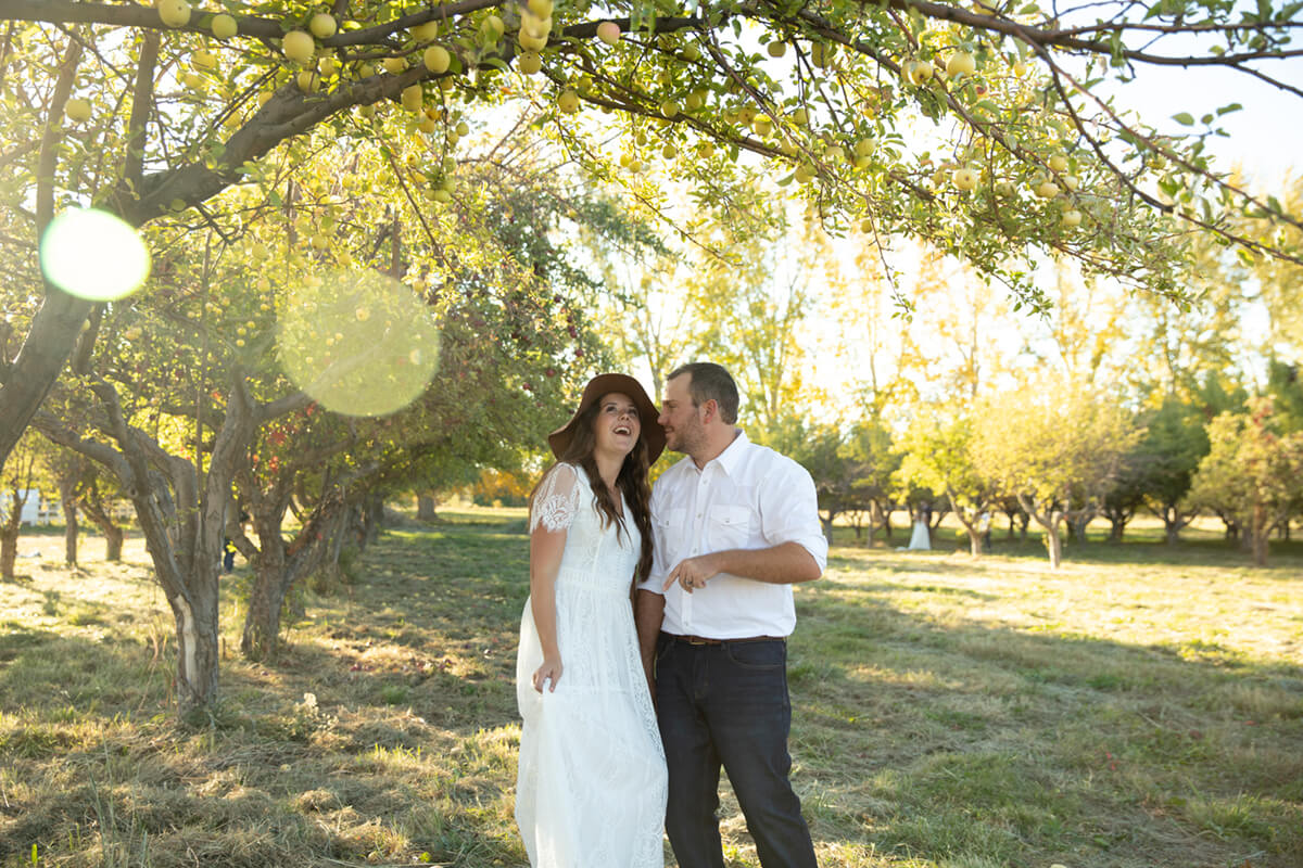 Image: Happy couple smiling in a green field under apple trees